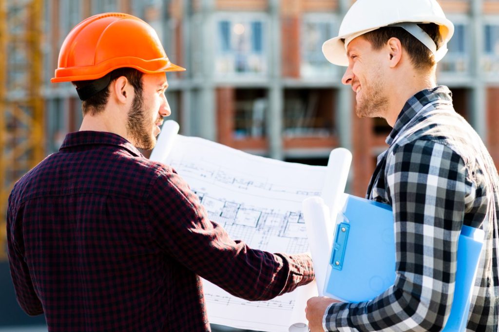 Dos hombres con un plano para dirigir una obra