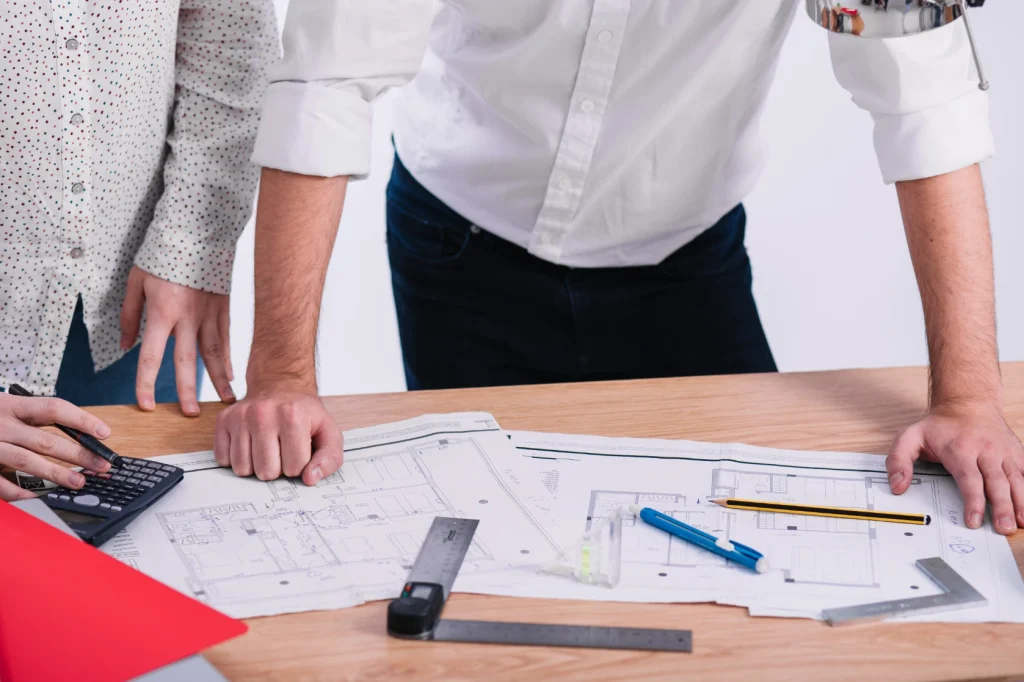 Dos personas con un plano arquitectónico para brindar soporte técnico